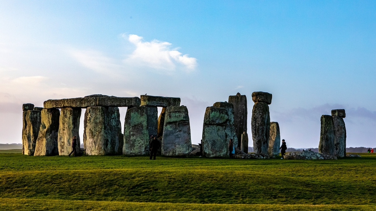 空の下、緑の平原に巨大な石が円状に並ぶ、イギリスの先史時代の遺跡ストーンヘンジの全景