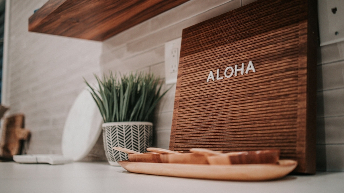 白を基調とした室内のカウンターに、観葉植物や「ALOHA」という白い文字が並べられた木製のサインボードが置かれている様子