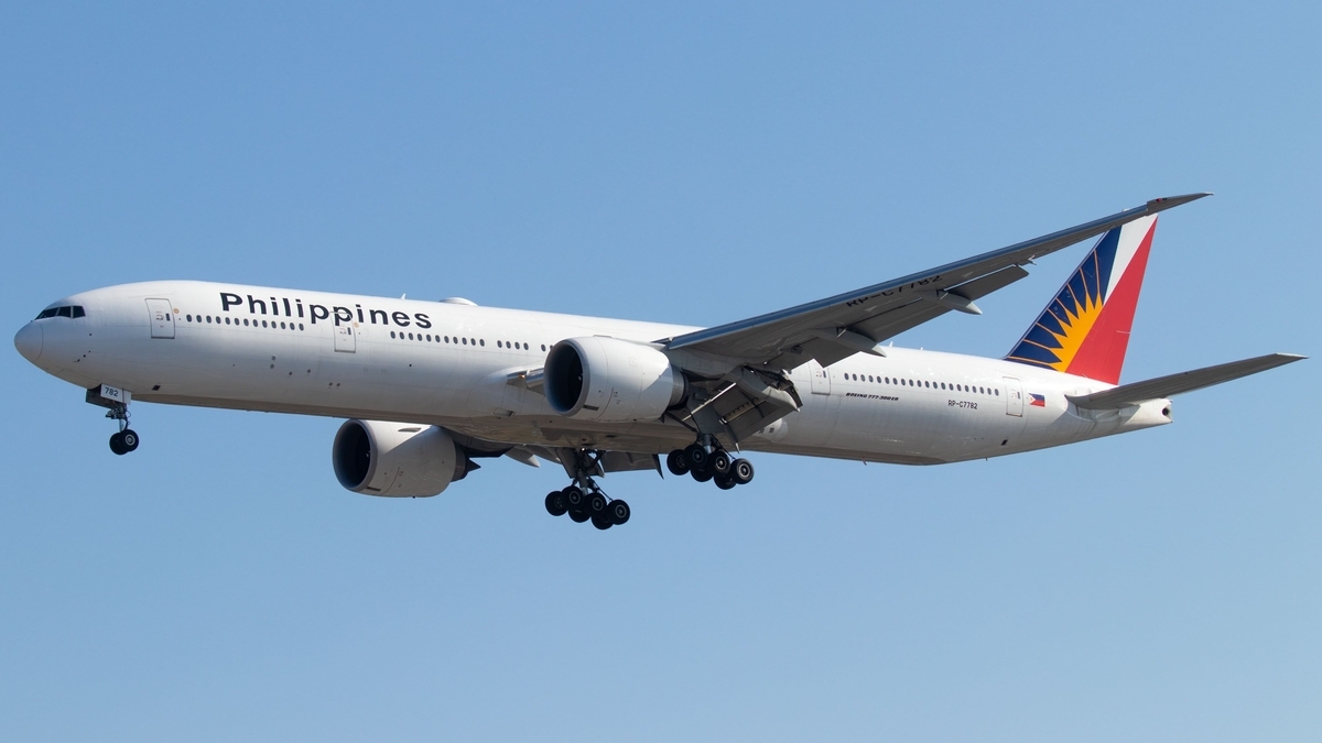 青空を背景に、車輪を出して飛行する、機体に「Philippines」と書かれたフィリピン航空の旅客機