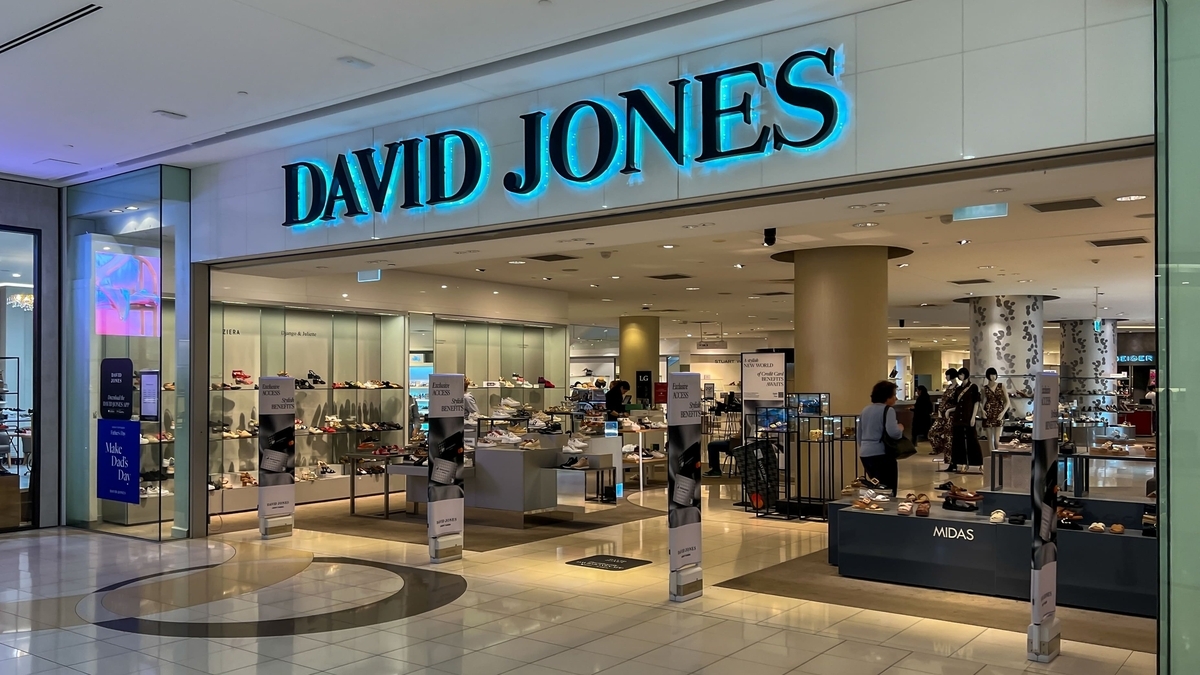 「DAVID JONES」という青く光る文字の看板が掲げられ、店内に靴やアパレル商品が並んでいる商業施設内の店舗の様子