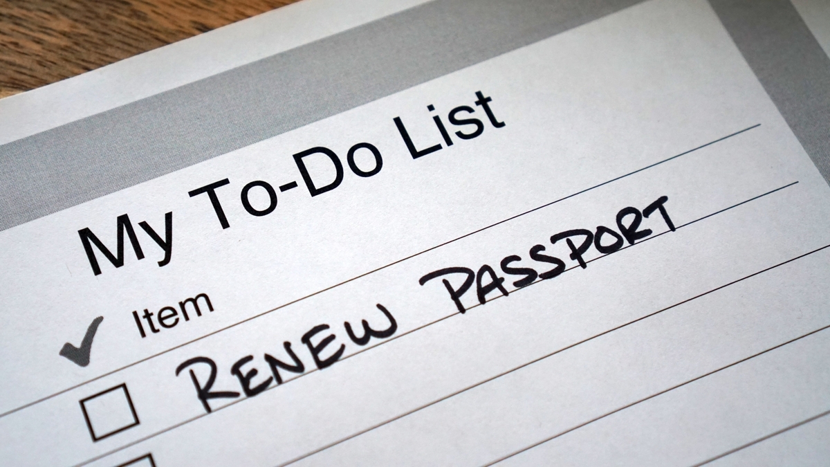木目の机の上に置かれた「My To-Do List」と印刷された用紙のアップ。「RENEW PASSPORT」と手書きされた項目のチェックボックスには、チェックマークが記入されている