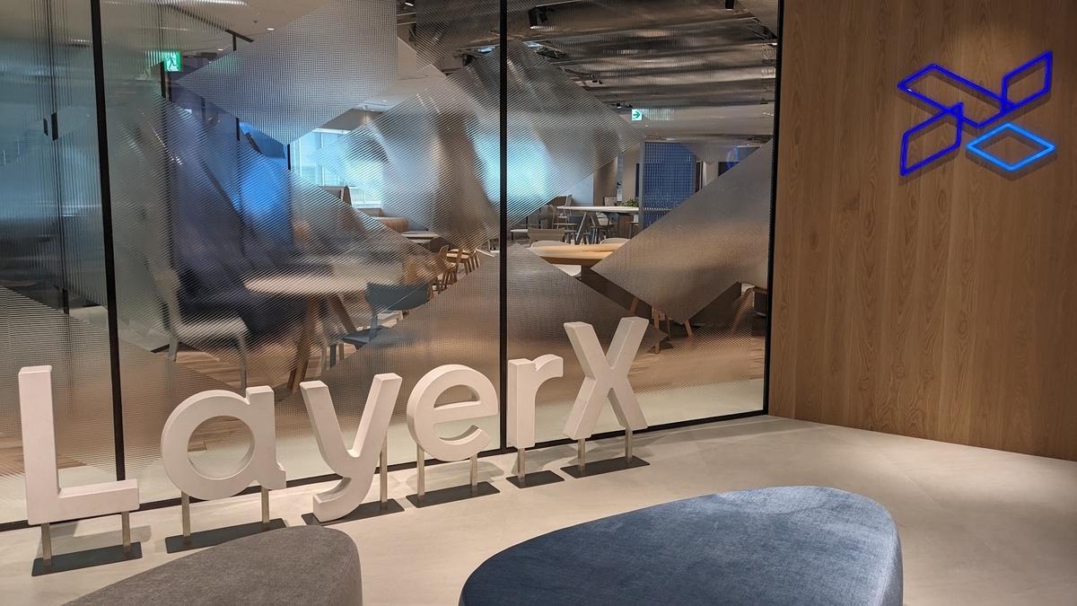 オフィスの入口を写した写真。正面の壁はガラス張りになっており、その手前にLayerXの文字の形をした白い立体的なオブジェが置かれている。