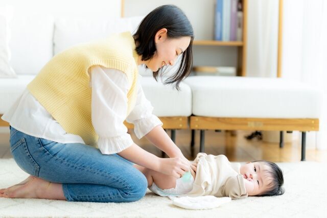 赤ちゃんのおむつを替えてあげてるママさん