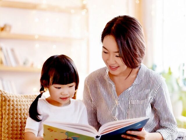 子供と一緒に絵本を読んであげるママ