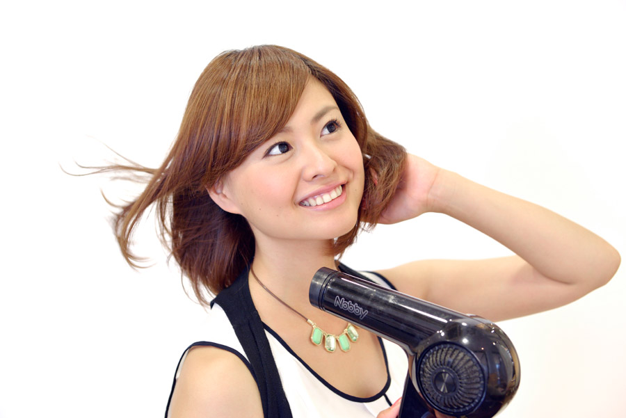 ドライヤーで髪を乾かす女性