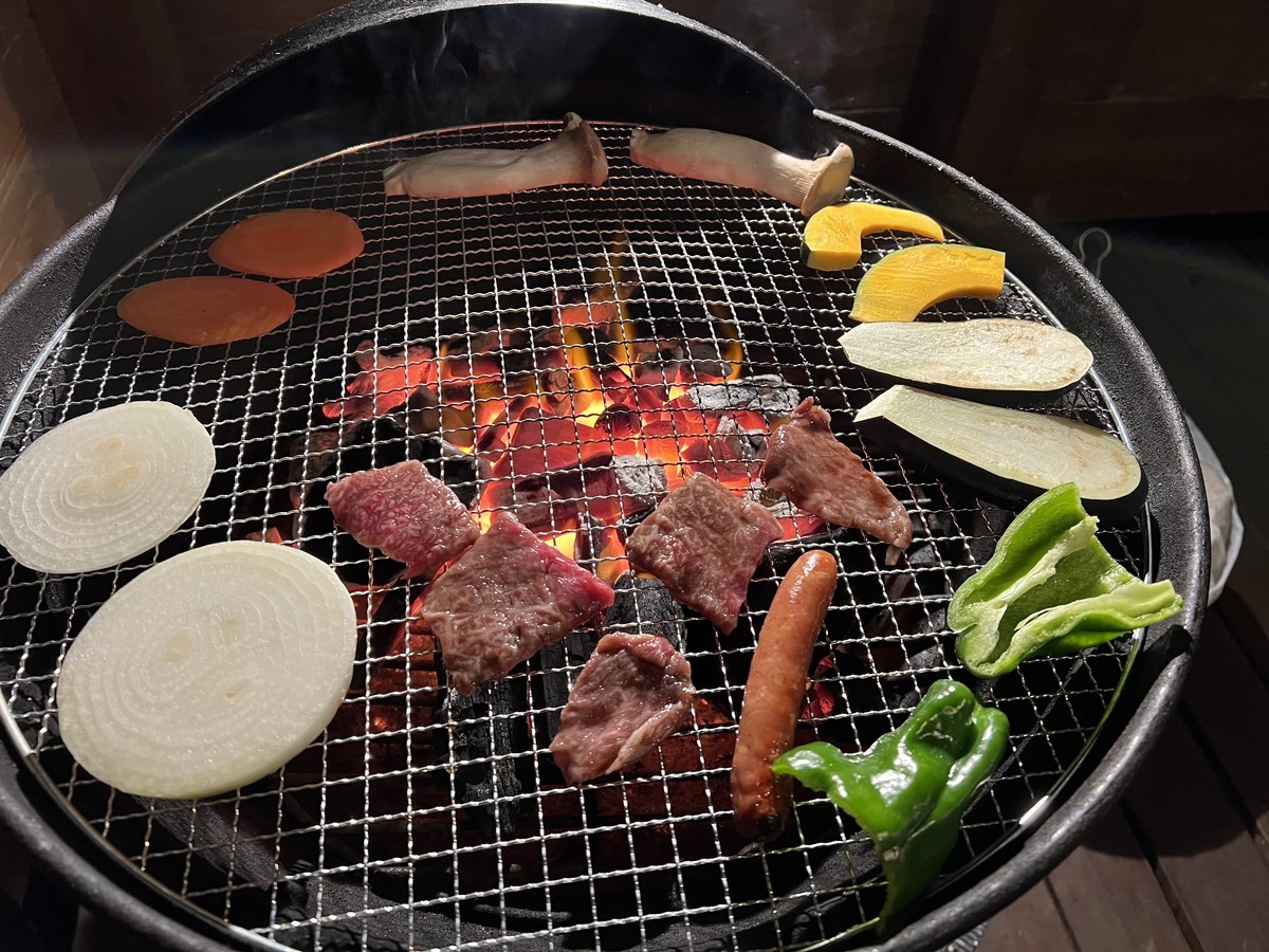 BBGコンロの上でお肉と野菜が焼けている写真