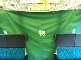 JR外房線の車内の一部が緑色の幕で区切られて「荷物車」として扱われている写真