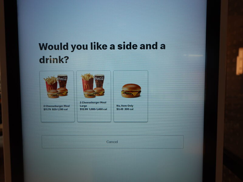 米国の McDonald's の注文端末でチーズバーガーを選択したときの画面の写真。「Would you like a side and a drink?」という問いの下に3つのボタンがある。第1の選択肢は「2 Cheeseburger Meal」というキャプションが付いており、内容はチーズバーガー2個・ポテトM・ドリンク。第1の選択肢は「2 Cheeseburger Meal Large」というキャプションが付いており、内容はチーズバーガー2個・ポテトL・ドリンク。第3の選択肢は「No, Item Only」というキャプションが付いており、内容はチーズバーガー1個のみ。