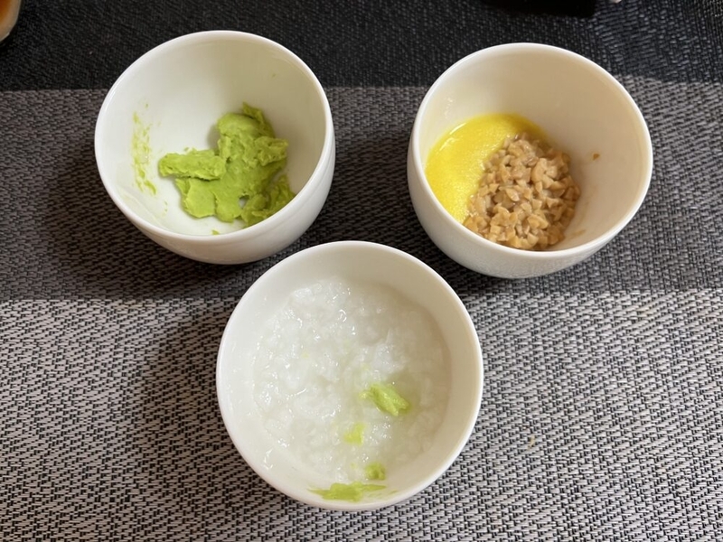 机の上に小さいお椀が3つ並べてある。それぞれお粥とすりつぶした枝豆、とうもろこしペーストと納豆が入っている。