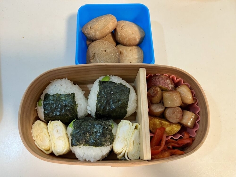 おにぎりや卵焼きが入ったお弁当と、クッキーが入った小さいタッパー。