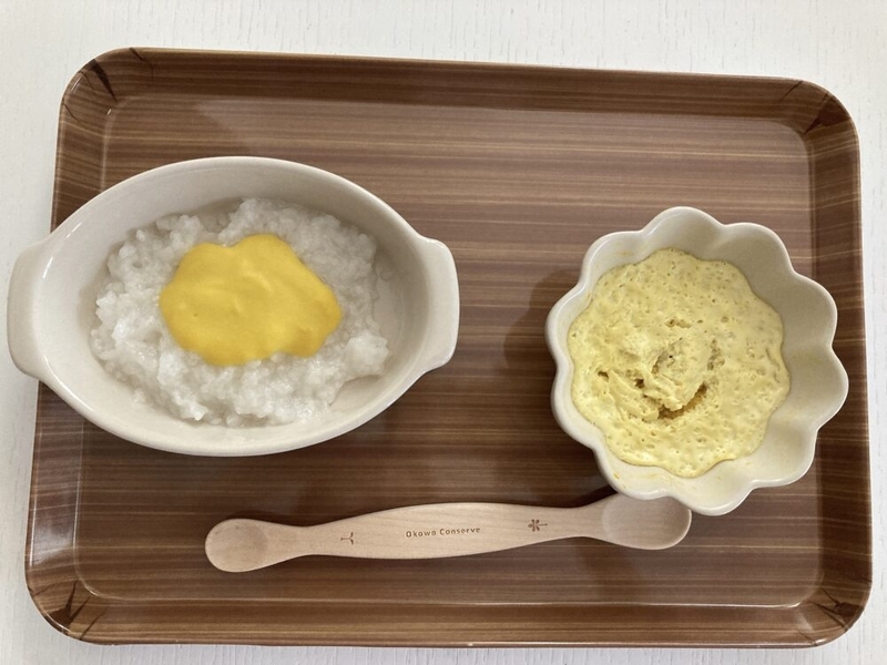お盆の上にお粥と茶碗蒸しがのっている。お粥の上にはとうもうもろこしペーストがかかっている。