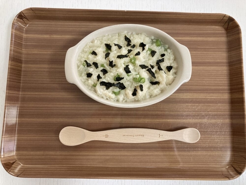 お盆の上にお皿に入った離乳食のうどんがのっていて、スプーンが添えられている。