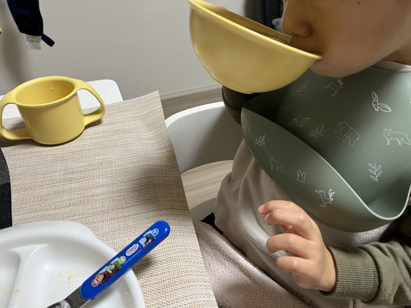 子供が黄色い茶碗でスープを飲んでいる。
