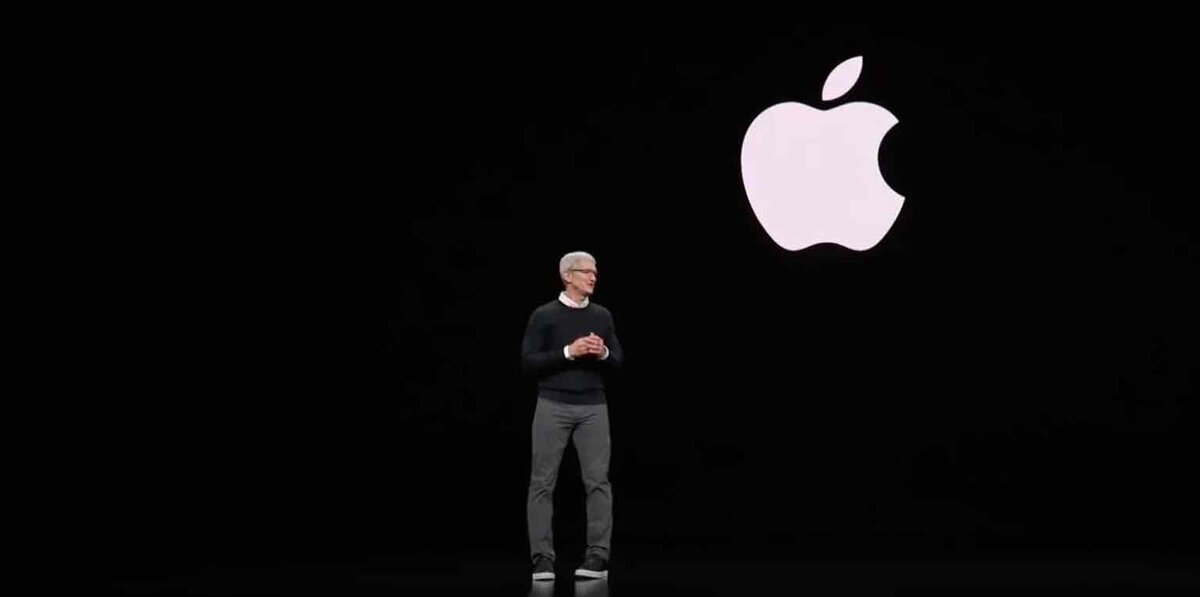 黒いステージ上で、背後に大きなAppleロゴを映しながらプレゼンテーションを行う人物