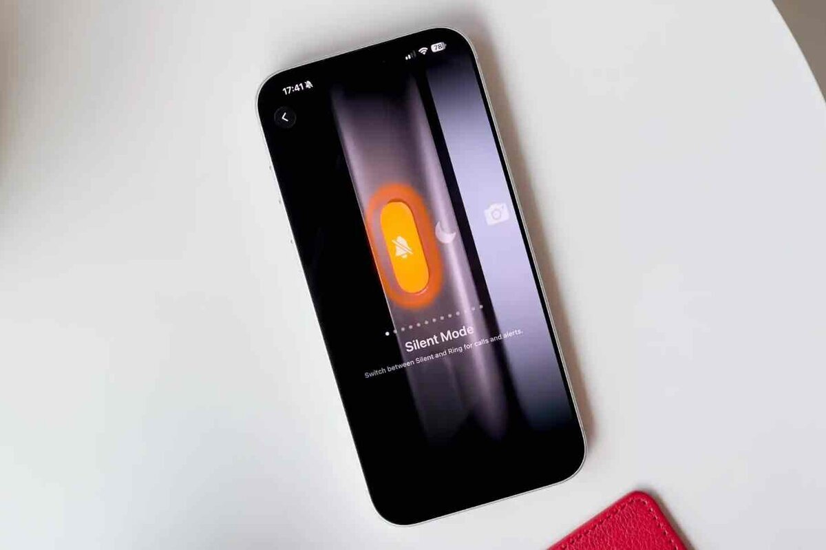 iPhoneの画面に表示されたサイレントモード切り替え画面。オレンジ色のミュートアイコンが点灯し、アクションボタン操作によるモード変更を示している。