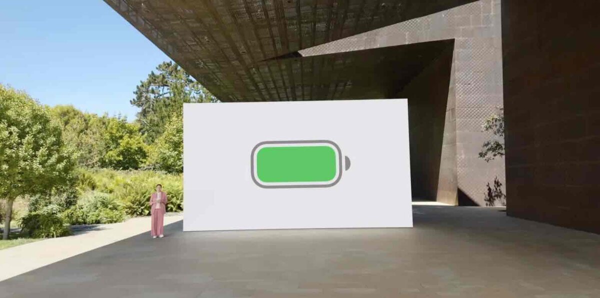 屋外ステージに大型スクリーンが置かれ、中央に緑色の満充電アイコンが大きく表示されている様子。左側には説明を行う人物が立っている