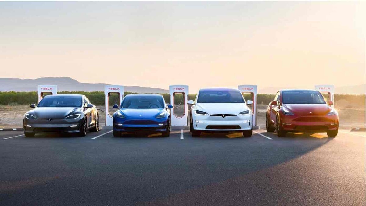 充電ステーションに並ぶ複数のTesla車。黒・青・白・赤の車体が夕日の光を受けて整列している様子