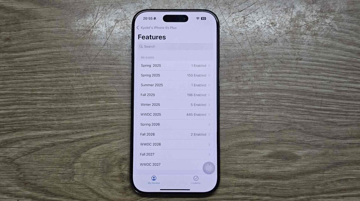 木目のテーブルの上に置かれたiPhoneの画面に、開発用の「Features」一覧が表示され、2025年〜2027年向けの内部機能フラグが並んでいる様子