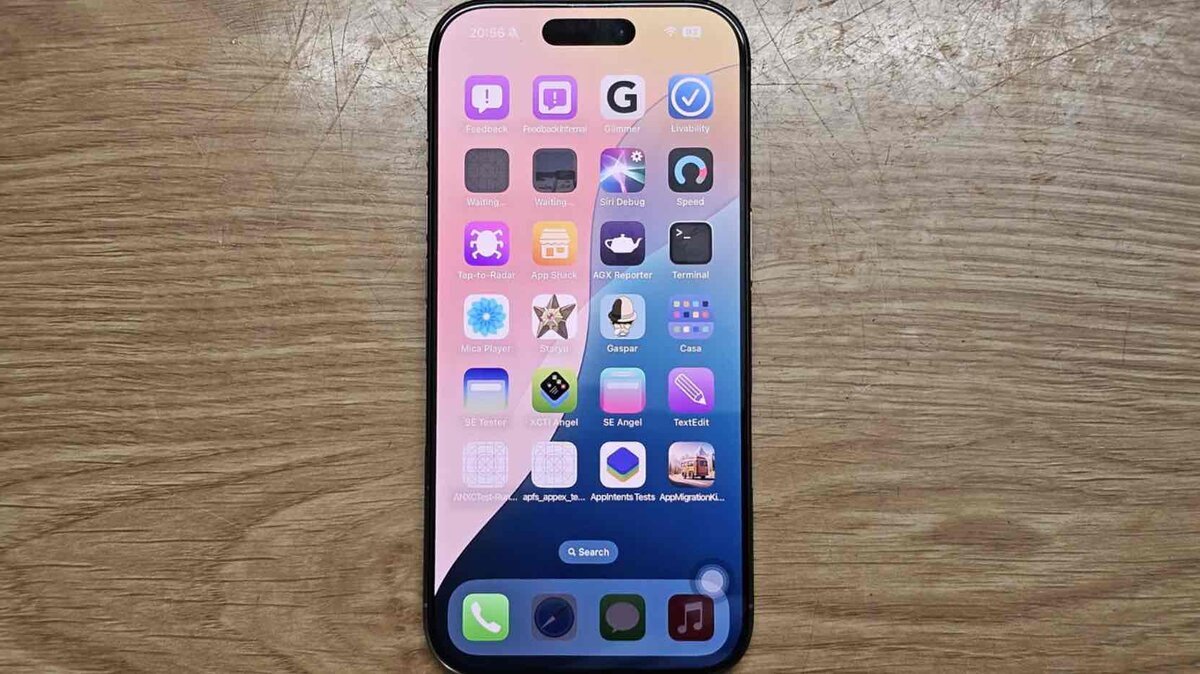 木目のテーブルの上に置かれたiPhoneの画面に、開発用アイコンがずらりと並び、内部テストアプリやデバッグ用ツールが表示されている様子