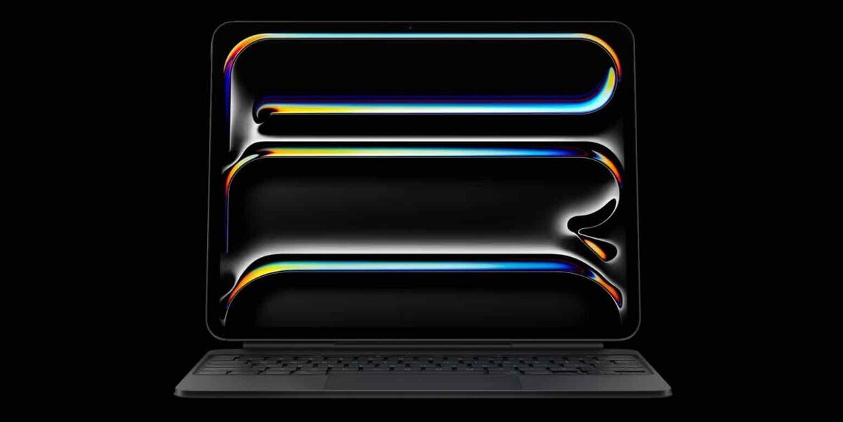 暗背景に浮かぶMacBookのディスプレイと、抽象的な光のビジュアル