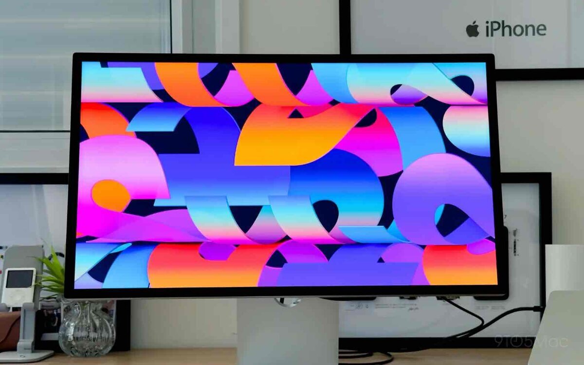 デスク上に設置された大型ディスプレイに、青・紫・オレンジを基調とした抽象的なカラフルグラフィックが表示されている様子