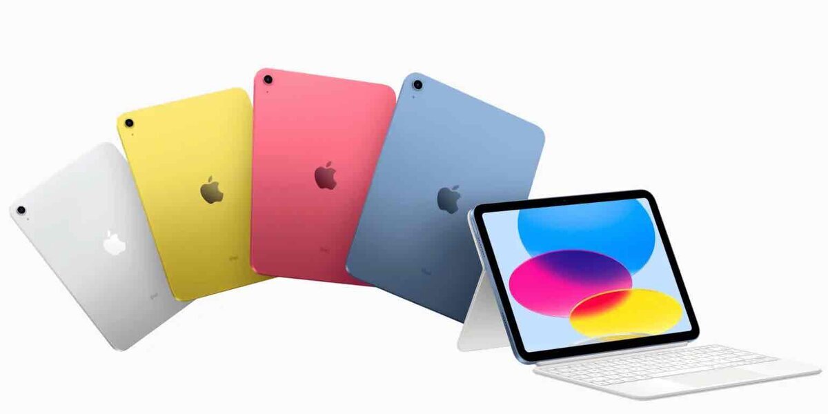カラーバリエーションの異なる無印iPadが背面から並び、手前にはMagic Keyboard Folioを装着したiPadが配置されたプロモーション画像。画面にはカラフルな円形の壁紙が表示されている