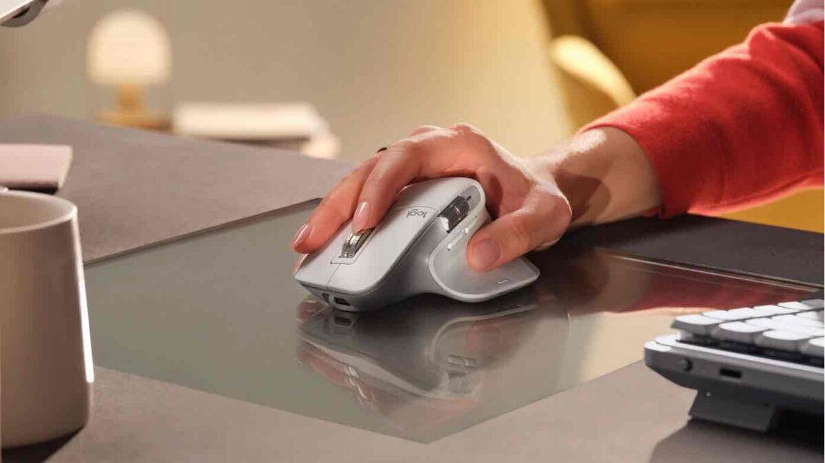 ガラス製のデスク上で、Logitechの高機能マウスを操作する様子。ボタン割り当てやスクロール設定をカスタマイズして使っているイメージ