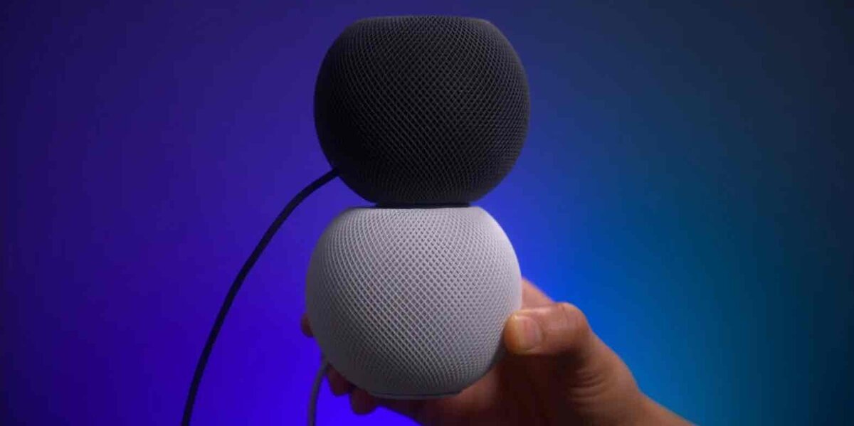スペースグレーとホワイトの2台のHomePod miniを上下に重ねて手に持っている様子。メッシュ状の外装と、丸みを帯びたコンパクトな形状が強調されている