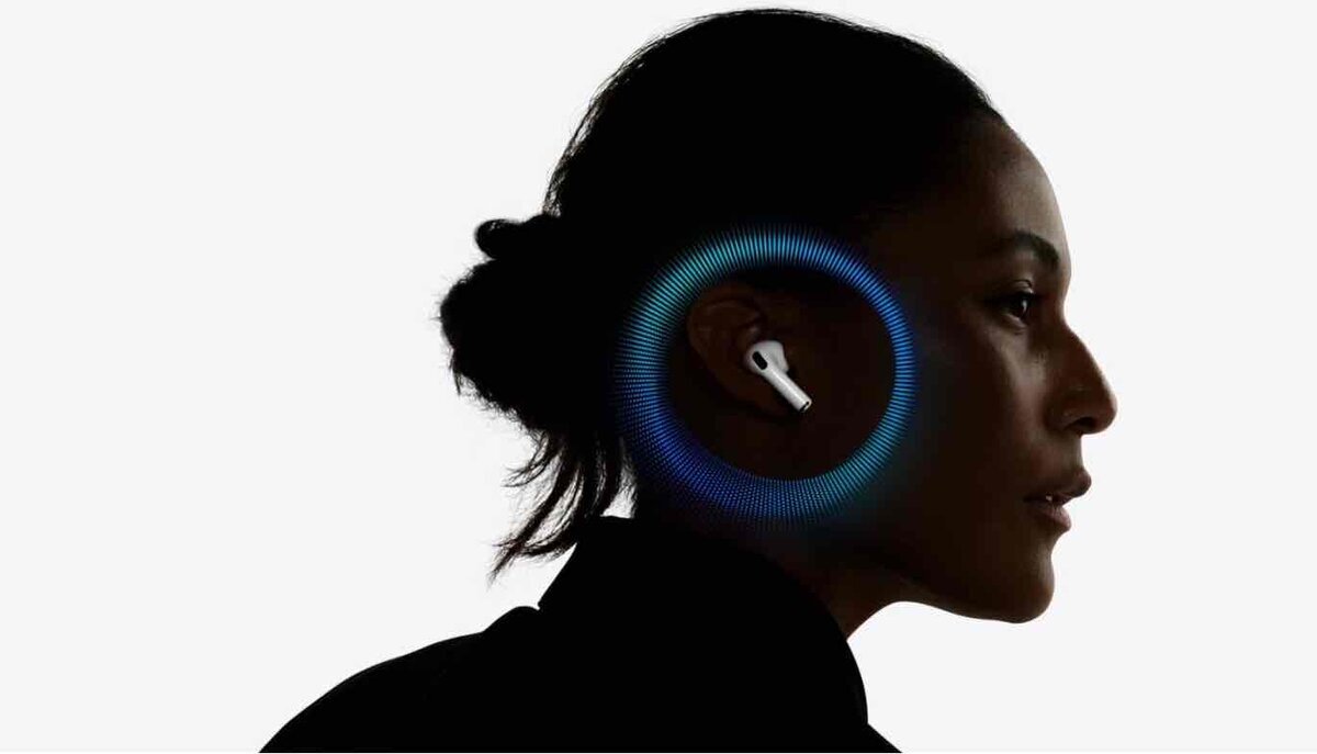 横を向いた女性の耳に装着された白いAirPods。耳の周囲には、空間オーディオを視覚的に表現した青い光の同心円状のグラフィックが描かれ、背景は白で統一されている