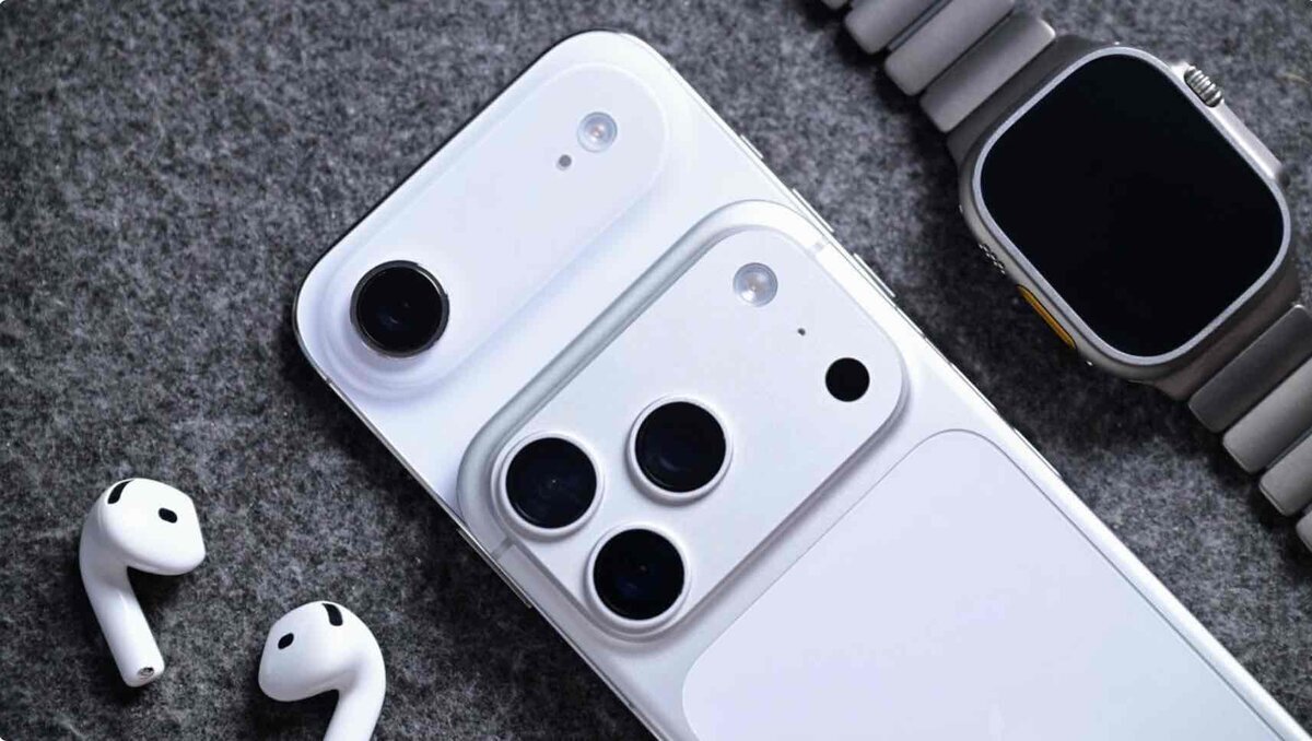 グレーのフェルトの上に配置された、ホワイトのiPhone 2機種(垂直デュアルカメラと3眼カメラ)、AirPods、およびリンクブレスレットを装着したApple Watch Ultraの俯瞰写真
