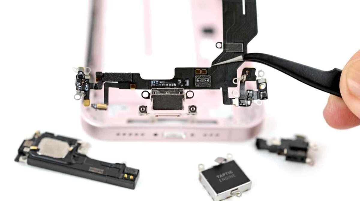 iPhone 17eの分解で取り外されたUSB-Cポート周辺のフレックスケーブルと内部パーツ構造を示したクローズアップ画像（修理性と部品配置の違いが分かる）
