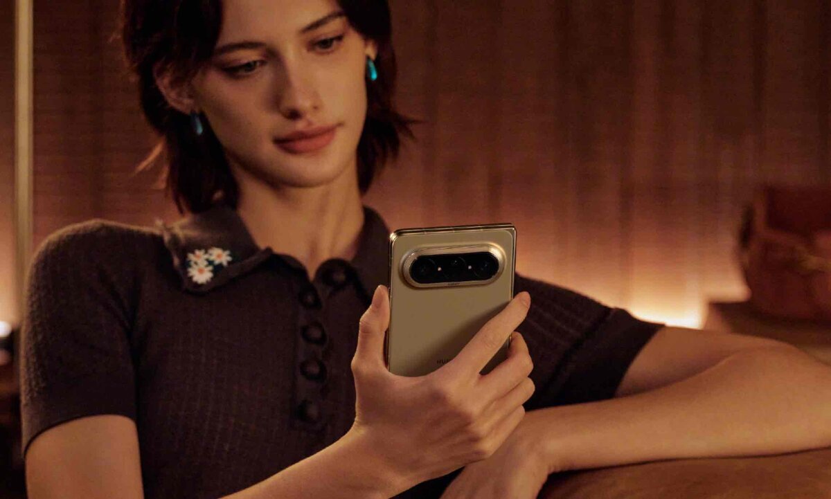 Huawei Pura X Maxを手に持つ女性。横に広いワイドな筐体設計と、背面の水平基調なトリプルカメラユニット、そして格子状のステッチが施されたベージュのヴィーガンレザー背面パネルのデザイン
