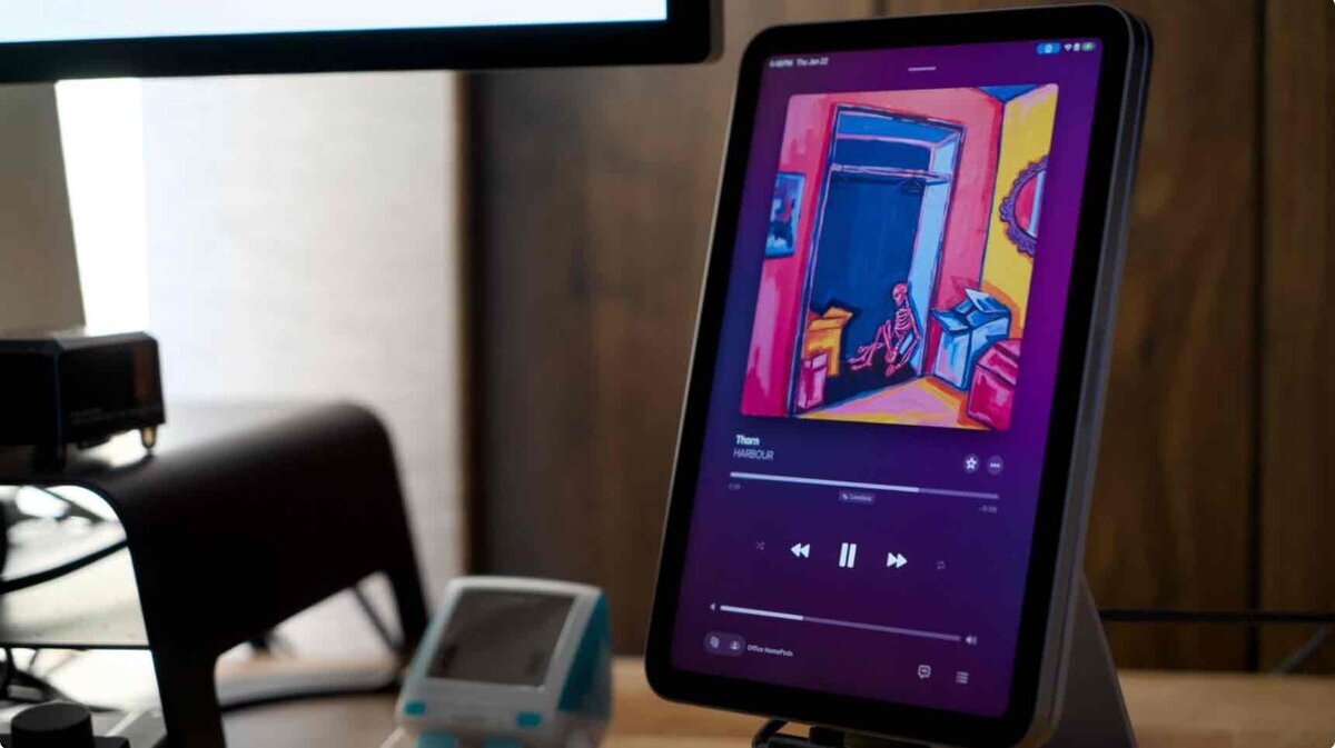 AppleのAIホームハブと噂されるスマートディスプレイ風タブレットが、スタンド上で音楽再生画面を表示しているイメージ