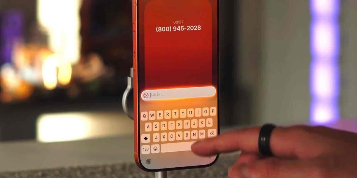 スタンドに固定されたiPhoneの通話画面で、画面下部に表示されたキーボードに指を近づけている画像