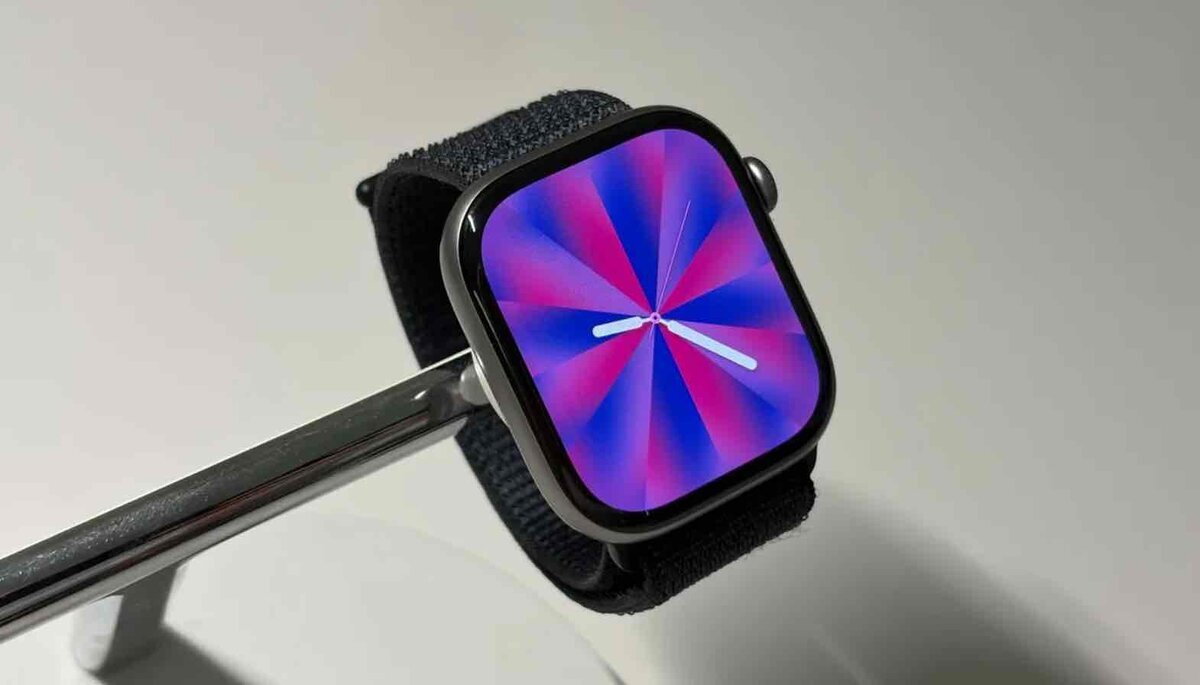 紫とピンクの放射状Pride Luminance文字盤を表示した、黒いバンド付きApple Watchの展示写真