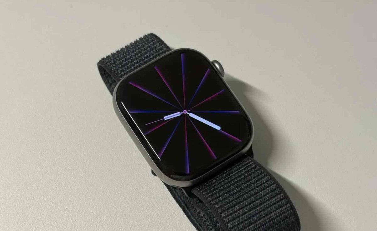 alt：暗い背景に紫と青の放射状ラインを表示したPride Luminance文字盤のApple Watch