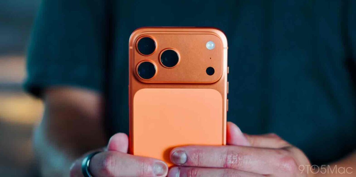 オレンジ色のiPhone Proの背面を手に持っている様子。大型カメラユニットと背面パネルの色の違いが見える