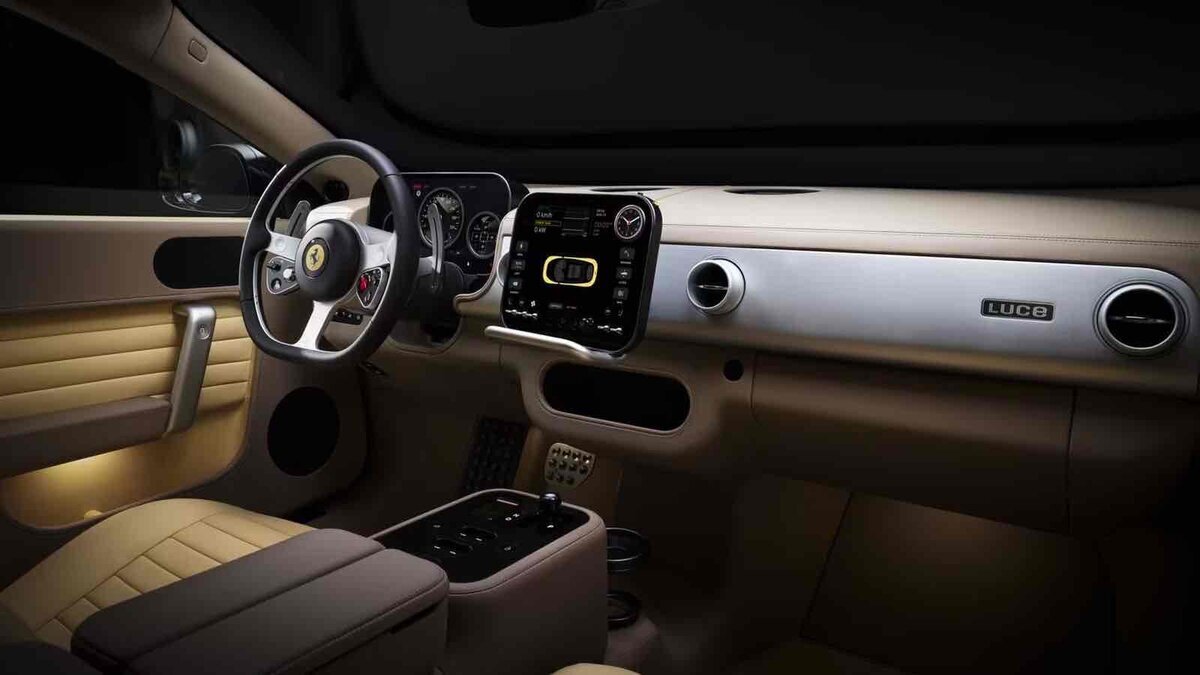 Ferrari Luceの車内を写した画像。3本スポークのステアリング、中央ディスプレイ、物理ボタン、ベージュ系の内装が見える