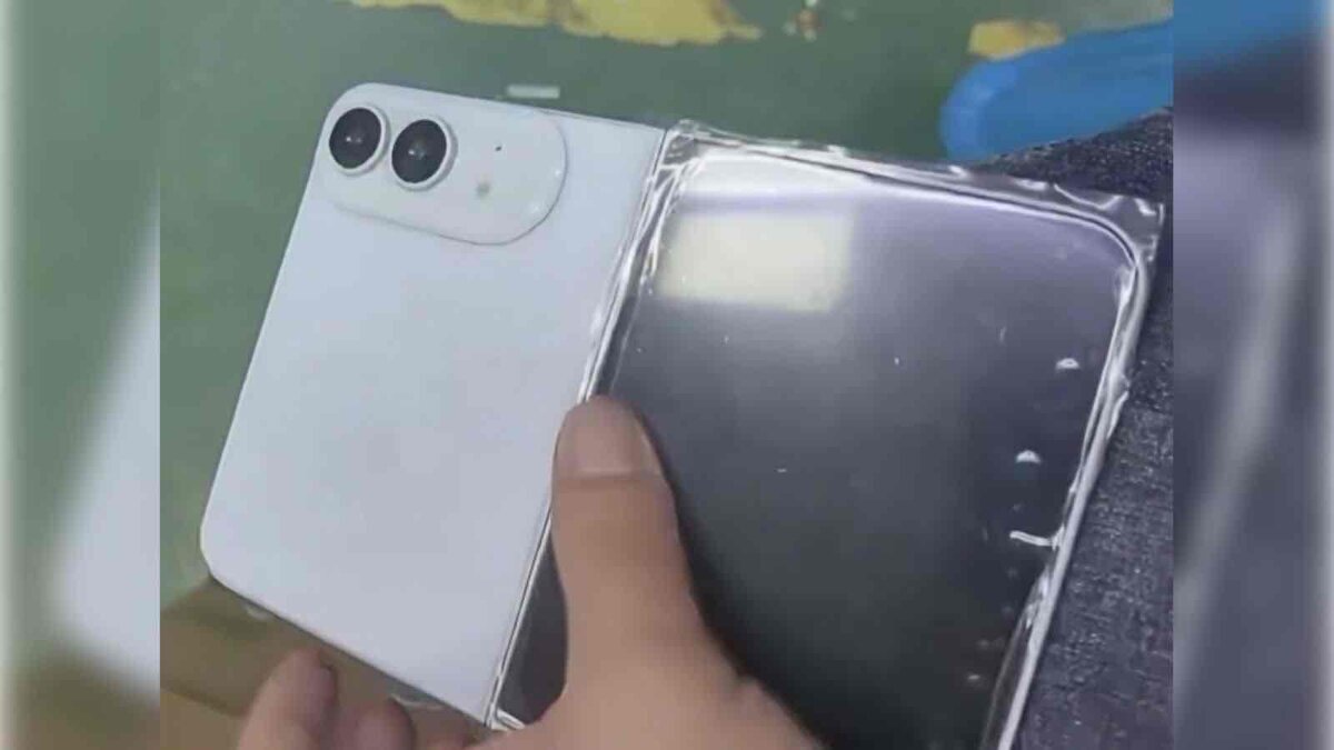 白い折りたたみ式iPhoneとみられる端末を開いた状態で手に持ち、背面のデュアルカメラと透明フィルム付きの画面側が見えている
