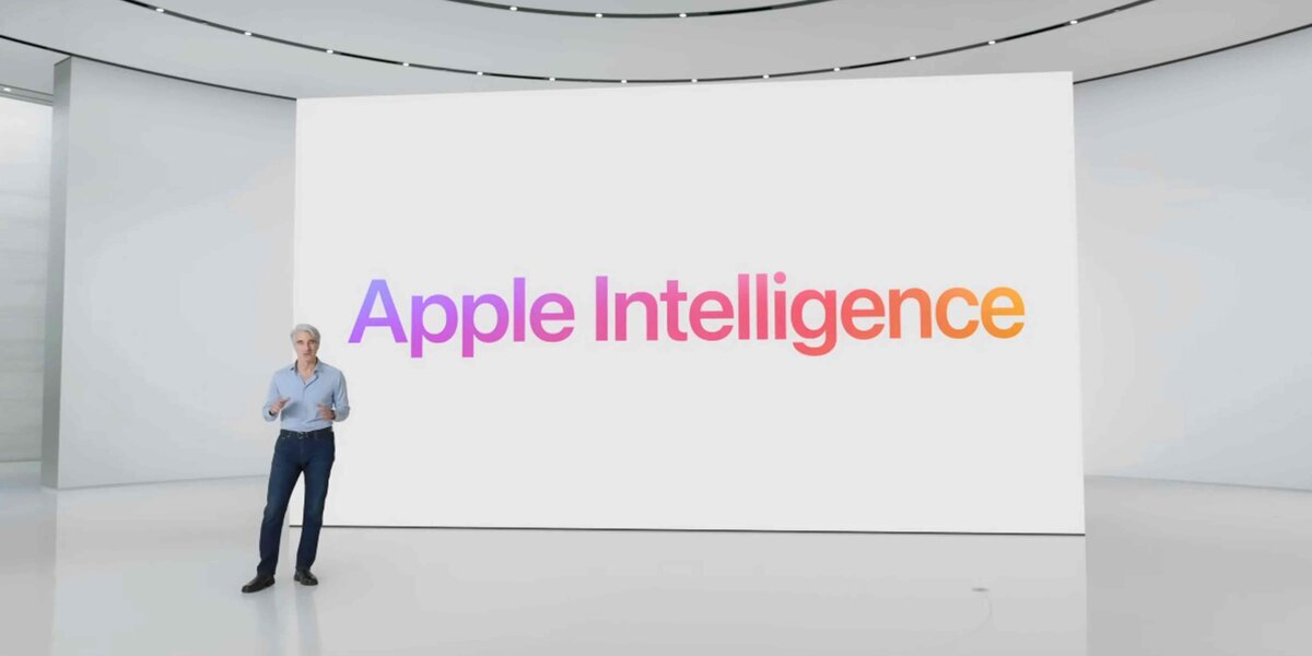 Appleのイベント会場で登壇者が立ち、後ろの大きなスクリーンに「Apple Intelligence」のカラフルな文字が映っている