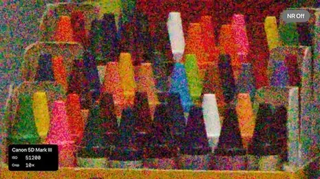 棚に並んだクレヨンをISO51200で撮った拡大画像。全面が赤や緑の細かいカラーノイズに覆われ、元の色や形がほとんど分からない。右上にNR Offの表示