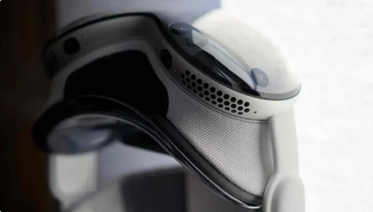Apple Vision Proを斜め後ろから寄って撮ったクローズアップ。白いライトシール部分の通気孔と、レンズ周りの黒いガラス面、頭の後ろへ回るバンドの付け根が写っている