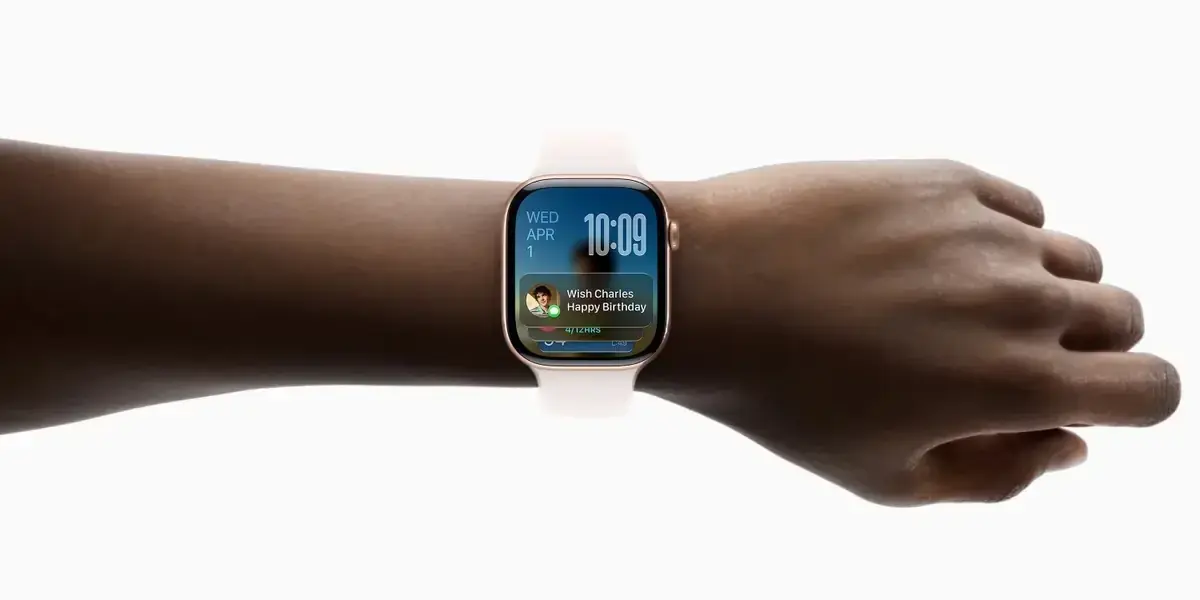 手首に着けた薄いピンクのApple Watchを横から見たところ。画面に重なったウィジェットにWish Charles Happy Birthdayという誕生日のリマインダーが表示されている