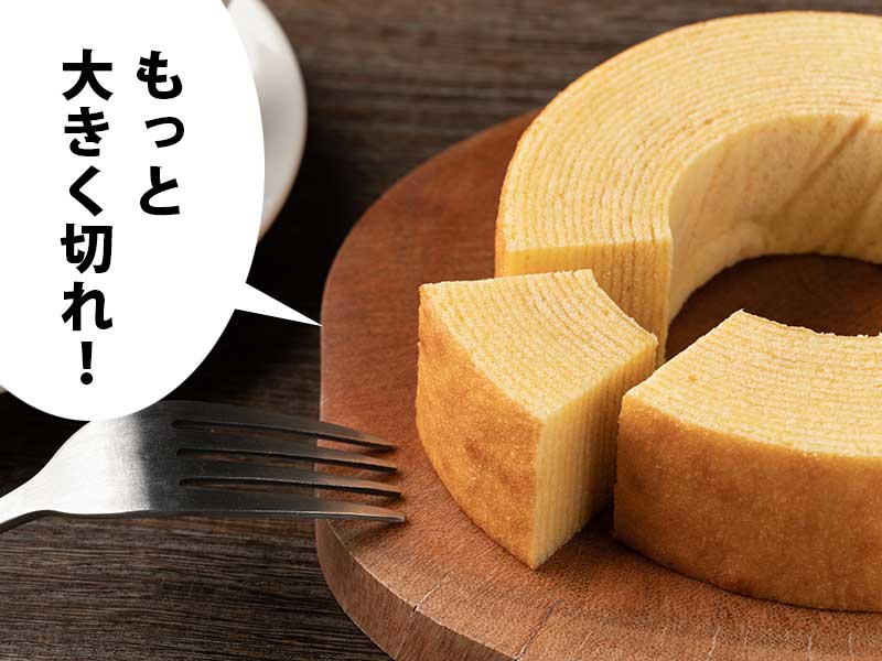 バームクーヘンと切り分けられたかけらとフォーク。吹き出しに『もっと大きく切れ！』