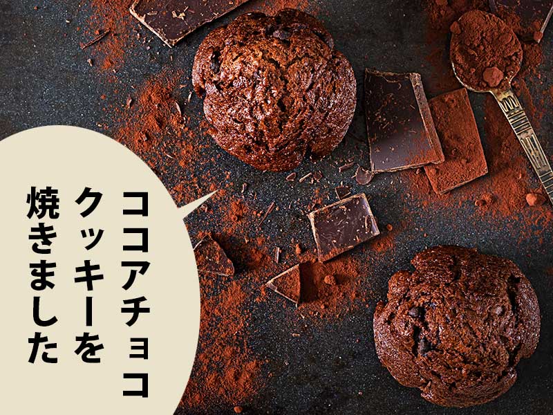 黒い台にココアチョコクッキーとチョコレート。吹き出しに『ココアチョコクッキーを焼きました』