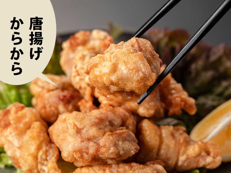 唐揚げの皿から1個箸でつまんだところ。吹き出しに「唐揚げからから」