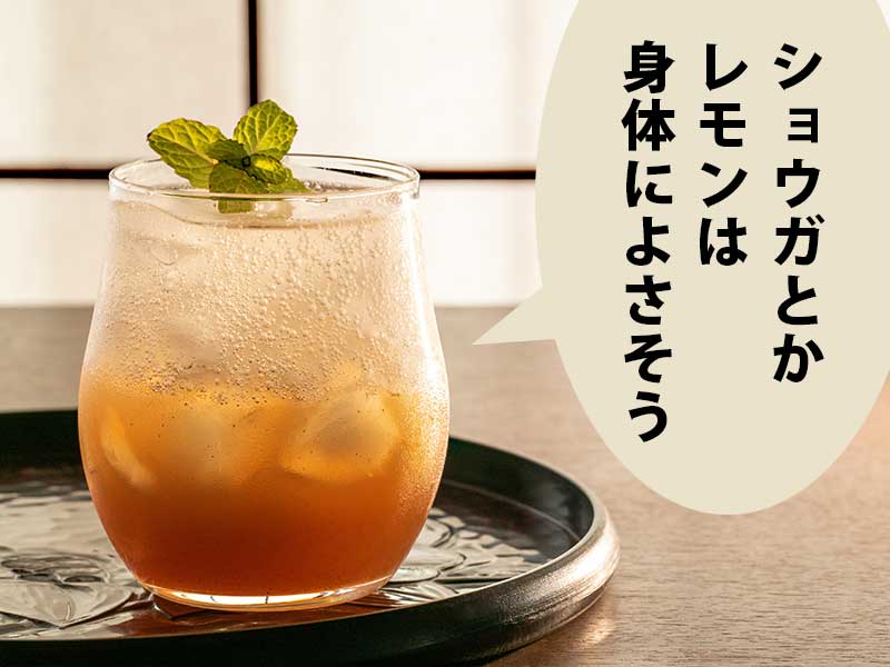 窓枠の手前に、茶色いシロップが沈んだ炭酸水を入れたカップを乗せた盆を置いた机。吹き出しに「ショウガとかレモンは健康によさそう」