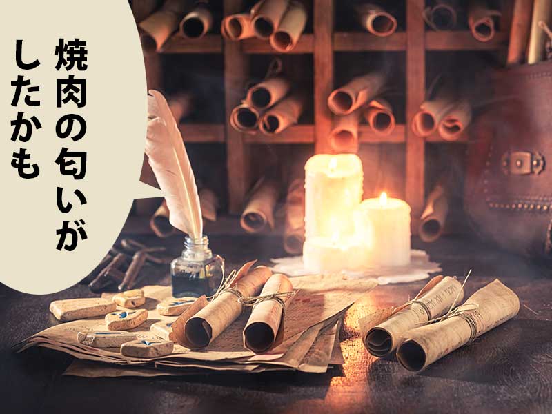 羊皮紙ロールを並べた棚の前に机。羽ペン、羊皮紙ロールが積まれた机にローソクがある。吹き出しに「焼肉の匂いがしたかも」