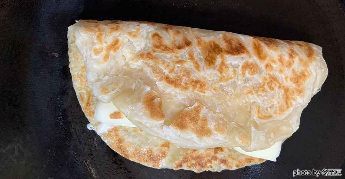 フライパン野中の半分に折ったパラタにチーズが挟まっている。
