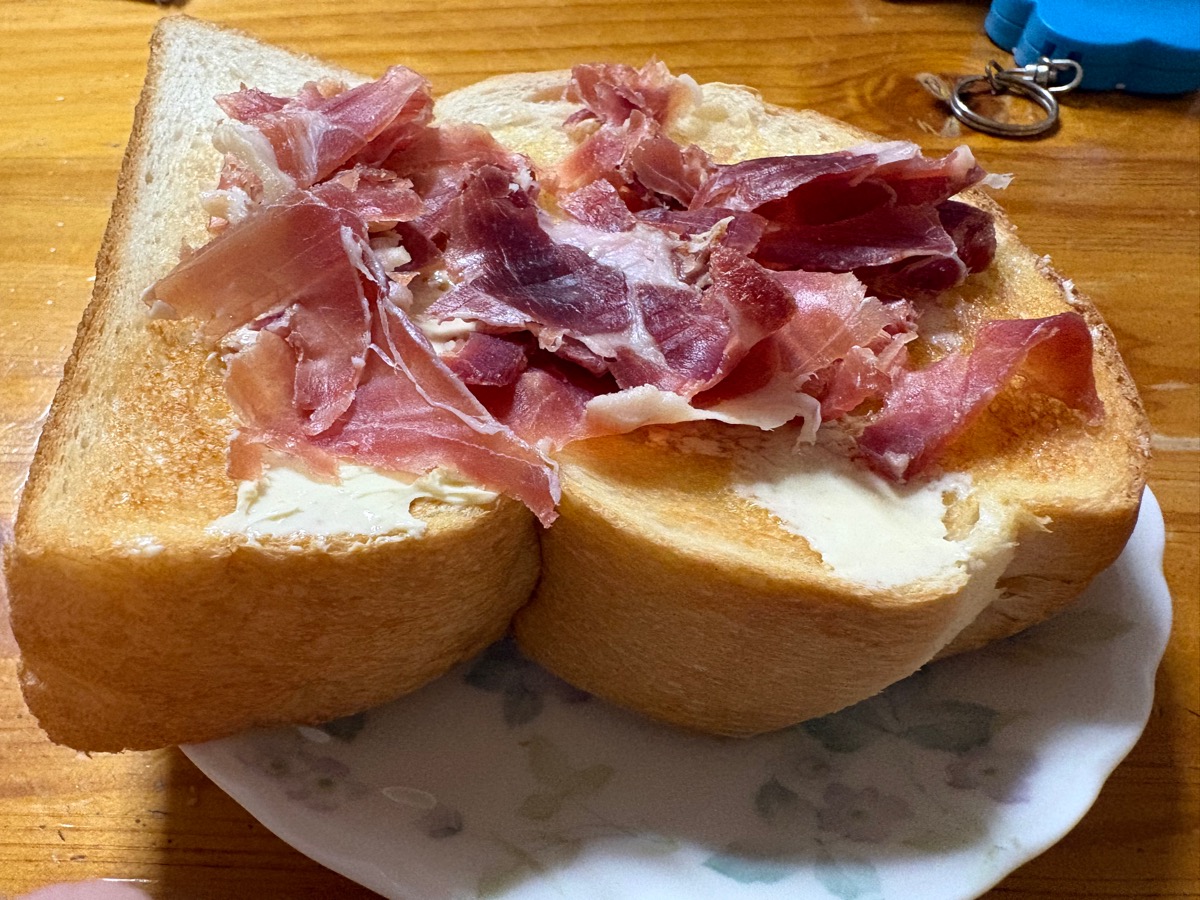 "雑な感じに生ハムの薄切りを載せたトーストの写真"